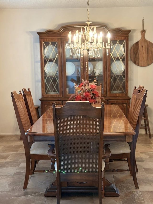 dining space featuring a notable chandelier, baseboards, a textured ceiling, and stone finish floor