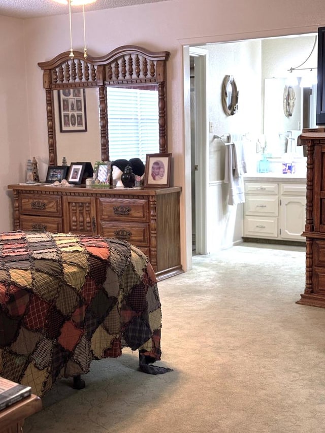 bedroom featuring light colored carpet, a textured ceiling, and ensuite bath