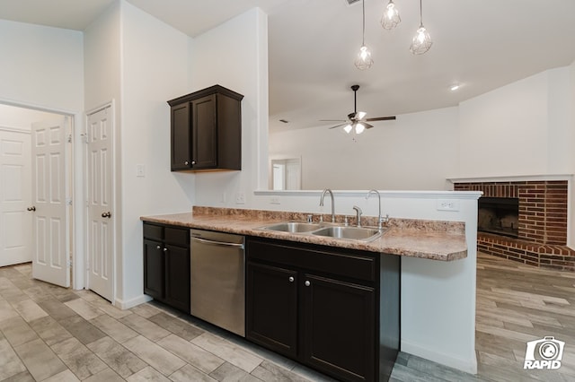 kitchen with a peninsula, a sink, a ceiling fan, stainless steel dishwasher, and a brick fireplace