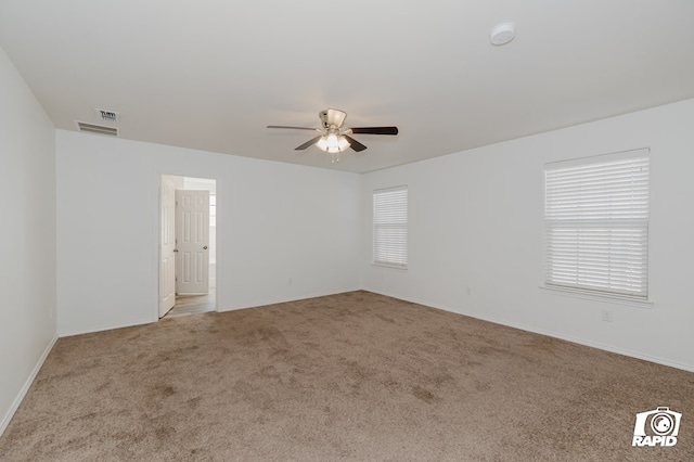 carpeted spare room with ceiling fan and visible vents