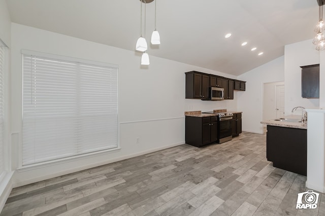 kitchen with lofted ceiling, stainless steel appliances, light wood-style floors, dark brown cabinets, and hanging light fixtures