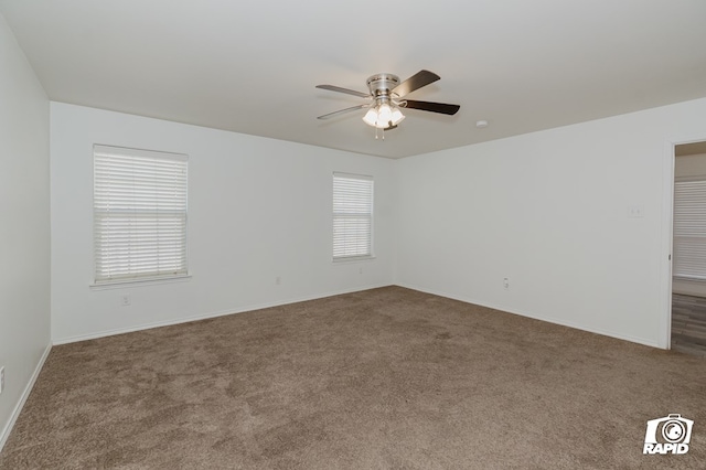 carpeted empty room with a ceiling fan and baseboards