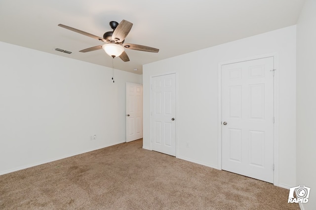 unfurnished bedroom featuring carpet floors, a ceiling fan, visible vents, and baseboards