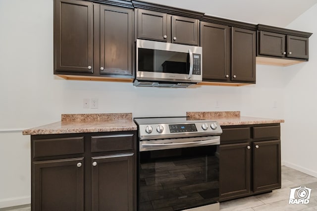 kitchen with stainless steel appliances, light countertops, dark brown cabinetry, and baseboards