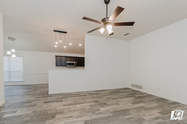 unfurnished room with baseboards, light wood-style flooring, visible vents, and a ceiling fan