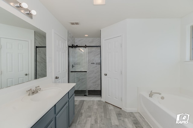 bathroom with visible vents, wood finished floors, a garden tub, vanity, and a shower stall