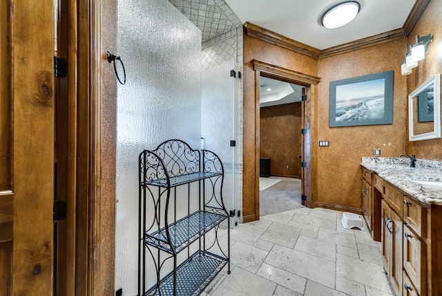 bathroom with stone tile flooring, crown molding, vanity, and baseboards