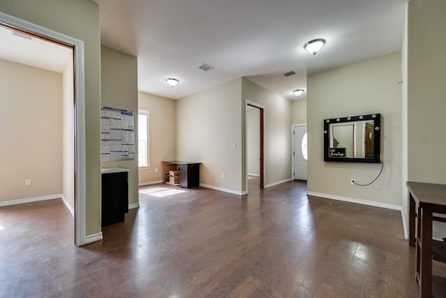 unfurnished living room featuring dark wood-type flooring, visible vents, and baseboards