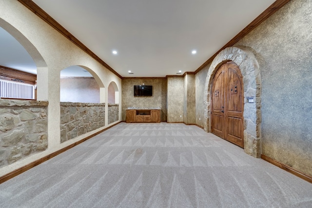 carpeted empty room with baseboards, arched walkways, crown molding, and recessed lighting