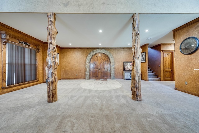 interior space with ornamental molding, arched walkways, carpet flooring, and stairs