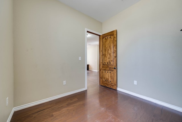 empty room with dark wood-type flooring and baseboards