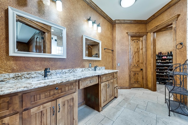 bathroom with double vanity, ornamental molding, a sink, and stone tile flooring