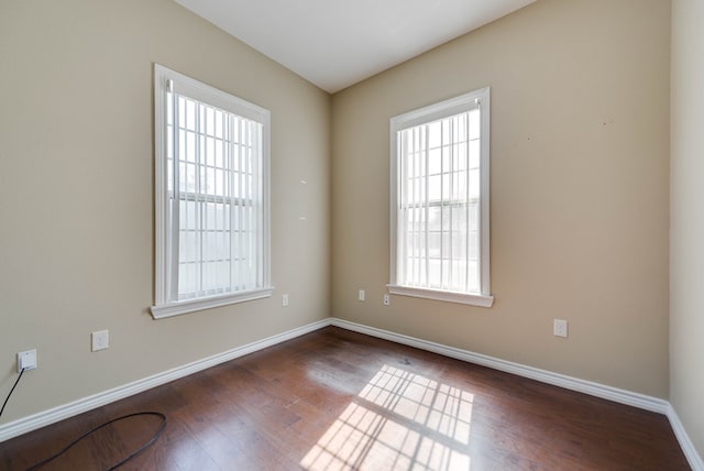 unfurnished room with a wealth of natural light, baseboards, and wood finished floors