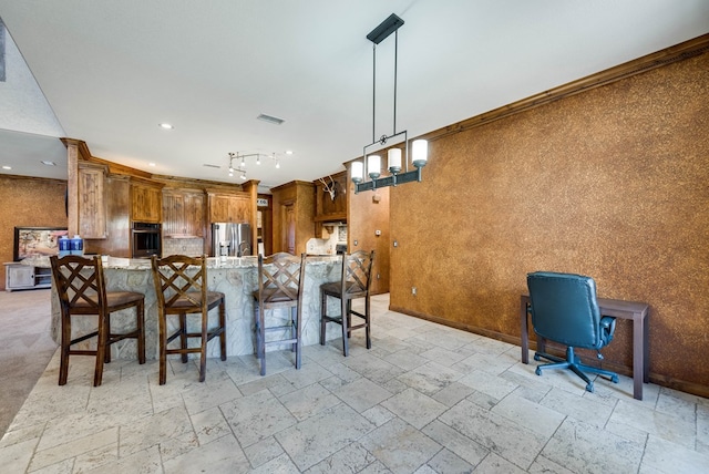 kitchen with brown cabinets, stone tile floors, stainless steel appliances, visible vents, and a kitchen breakfast bar