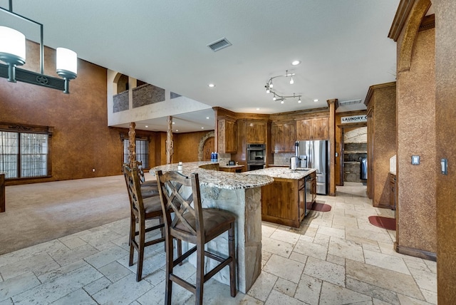 kitchen featuring stone tile floors, visible vents, light stone counters, stainless steel appliances, and recessed lighting