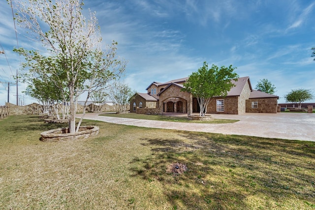 view of front facade with stone siding, a front lawn, and curved driveway