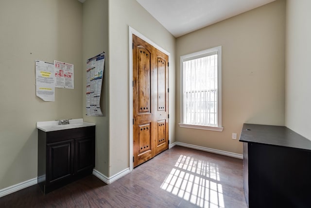 doorway featuring baseboards and dark wood-type flooring