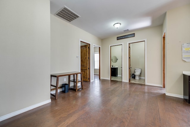 empty room featuring wood finished floors, visible vents, and baseboards