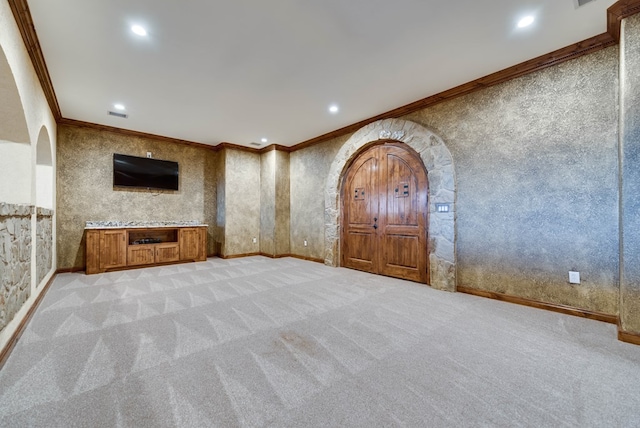 unfurnished living room with arched walkways, crown molding, light colored carpet, and wallpapered walls