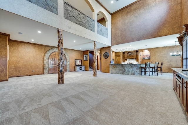 unfurnished living room featuring wallpapered walls, ornamental molding, carpet, a high ceiling, and recessed lighting