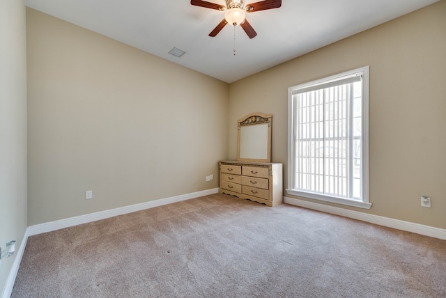 spare room with a ceiling fan, carpet flooring, visible vents, and baseboards