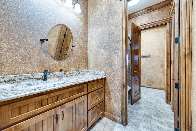 bathroom with ornamental molding, vanity, and baseboards