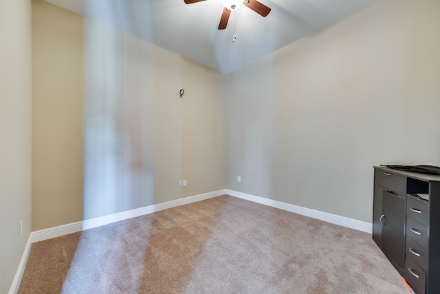 spare room with baseboards, a ceiling fan, and light colored carpet