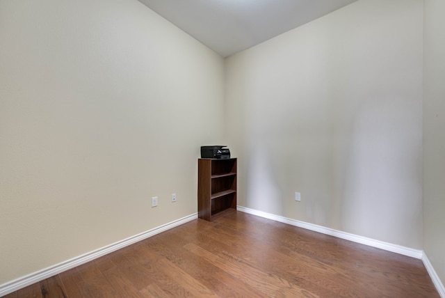 spare room with dark wood-type flooring and baseboards