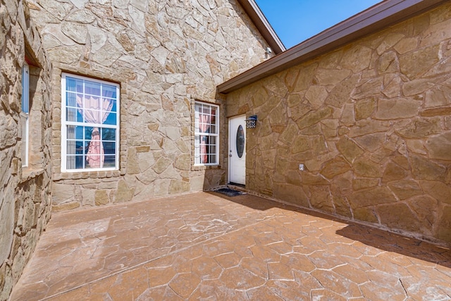 doorway to property featuring a patio area and stone siding