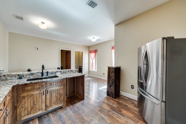 kitchen with a sink, stainless steel fridge, visible vents, and dark wood-style floors