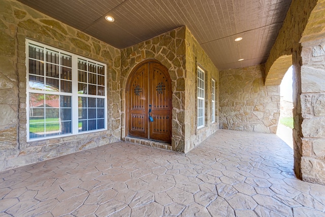 property entrance featuring stone siding and covered porch