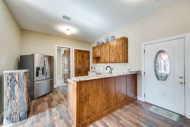 kitchen with brown cabinets, stainless steel refrigerator with ice dispenser, white electric range oven, visible vents, and a peninsula