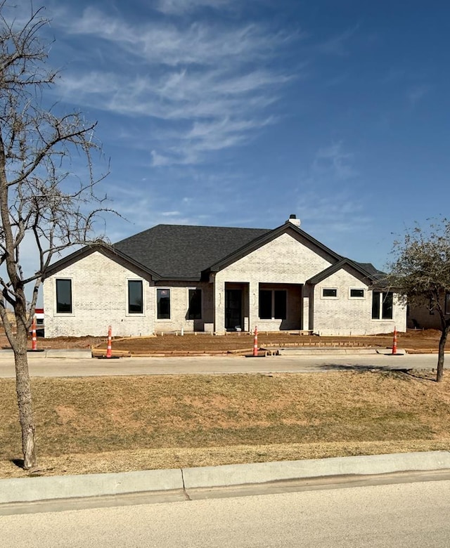 view of front of home with a front yard and roof with shingles