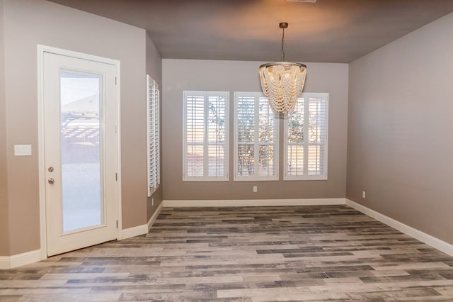 unfurnished dining area featuring a chandelier and hardwood / wood-style floors