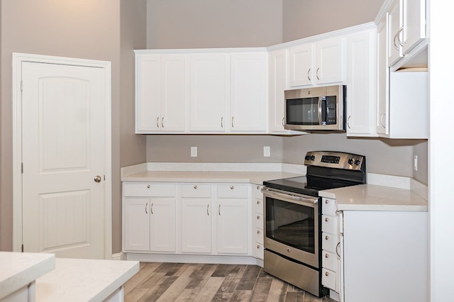 kitchen with white cabinets, light hardwood / wood-style floors, and appliances with stainless steel finishes