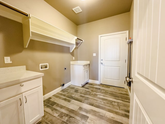 washroom with electric dryer hookup, washer hookup, cabinets, and light wood-type flooring