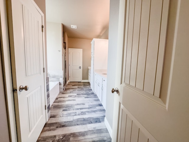 bathroom featuring a tub, vanity, and hardwood / wood-style flooring