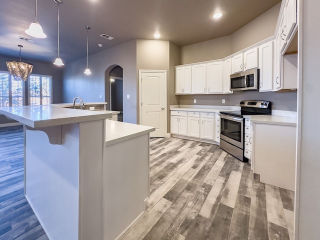 kitchen with white cabinets, a center island with sink, light hardwood / wood-style flooring, a notable chandelier, and stainless steel appliances