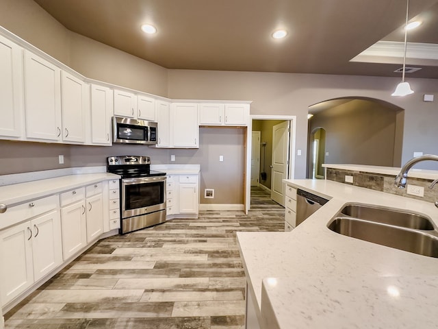 kitchen featuring stainless steel appliances, white cabinetry, hanging light fixtures, and sink