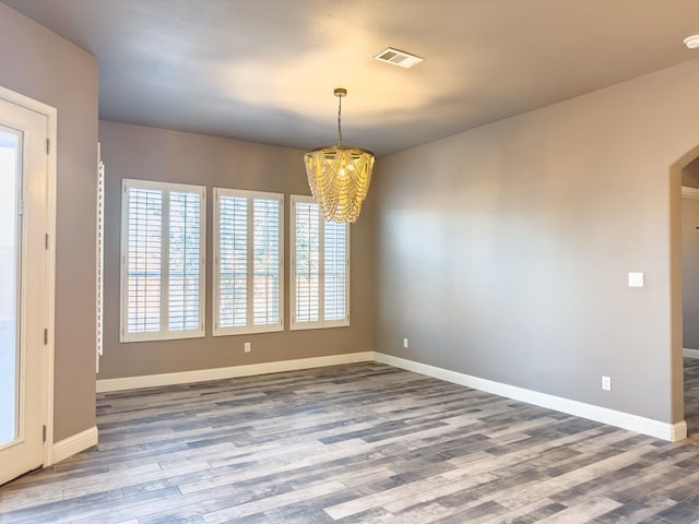 empty room featuring hardwood / wood-style floors and a notable chandelier