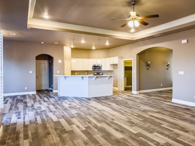 kitchen featuring white cabinetry, hardwood / wood-style floors, pendant lighting, a tray ceiling, and ornamental molding