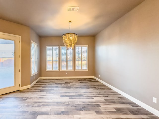 unfurnished dining area featuring light hardwood / wood-style floors and an inviting chandelier