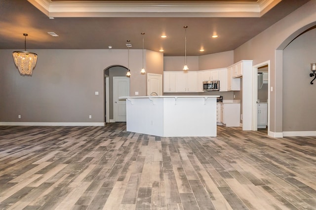 kitchen with white cabinetry, light hardwood / wood-style flooring, a large island, and ornamental molding