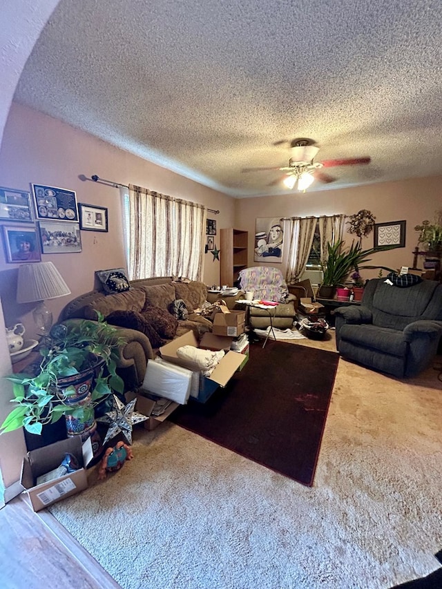 carpeted living room featuring ceiling fan and a textured ceiling