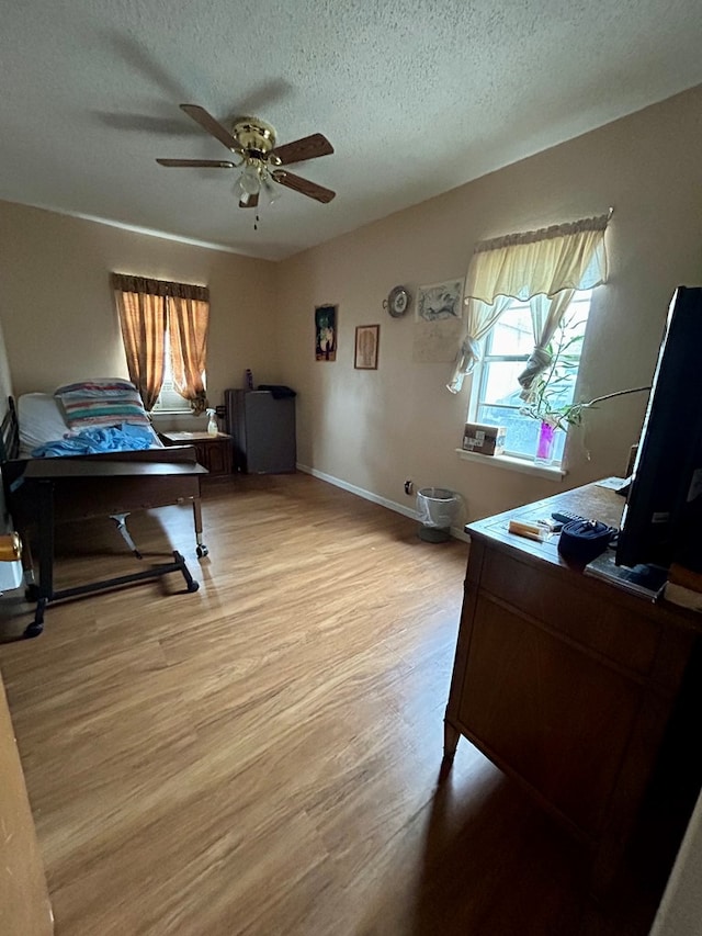 interior space with ceiling fan, light hardwood / wood-style floors, and a textured ceiling