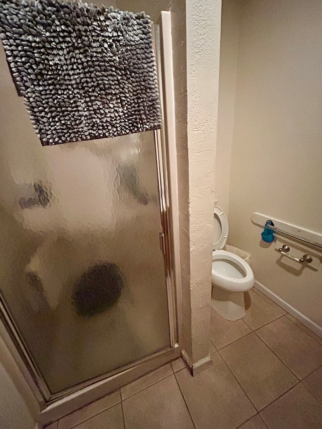 bathroom featuring tile patterned floors, a shower with shower door, and toilet