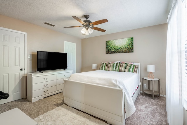 bedroom with a textured ceiling, ceiling fan, and light carpet