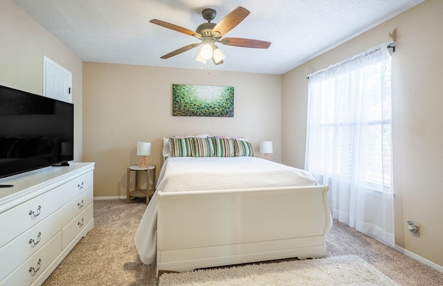 bedroom featuring ceiling fan, light carpet, and a textured ceiling