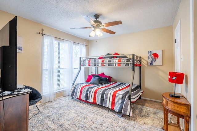 carpeted bedroom with ceiling fan and a textured ceiling