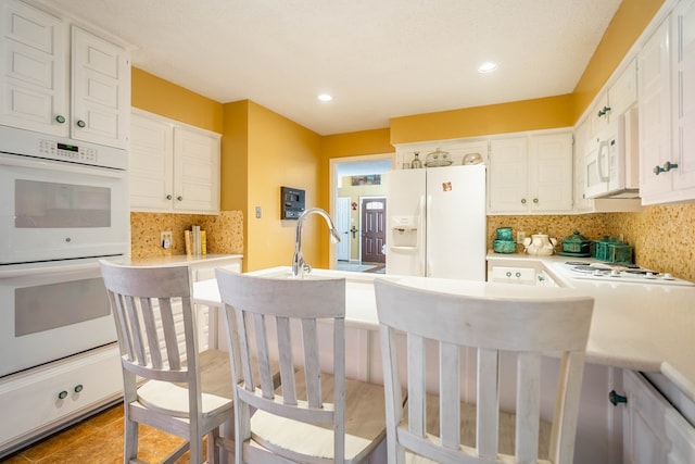 kitchen with backsplash, a textured ceiling, white appliances, sink, and white cabinets